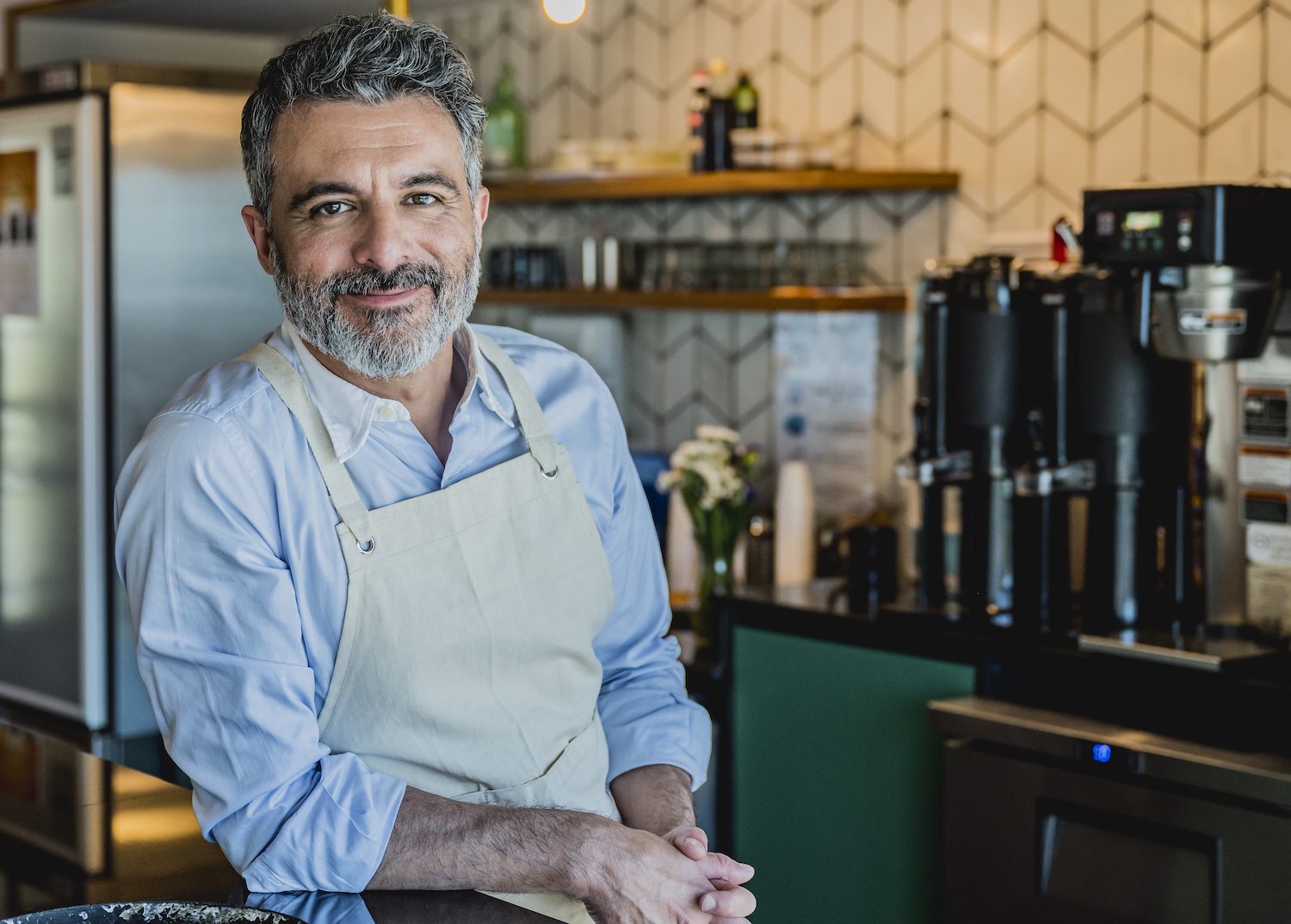 Smiling male barista ready to prepare drink in coffee bar