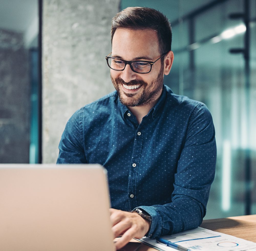 Smiling businessman using laptop in the office